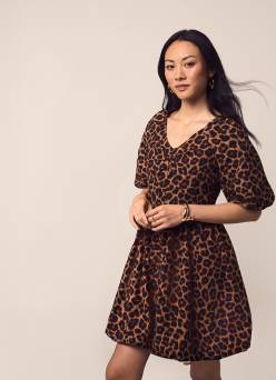 A woman is shown wearing a leopard print V-neck bubble hem mini dress with three-quarter sleeves.