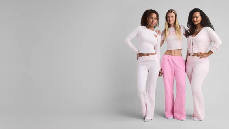 Three young women in pink outfits are standing next to one another.