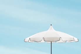 A white patio umbrella against a blue sky.