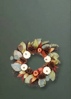 Image of a fall wreath made of faux foliage, including green leaves, pinecones and mini pumpkins. Autum wreaths. Shop now.