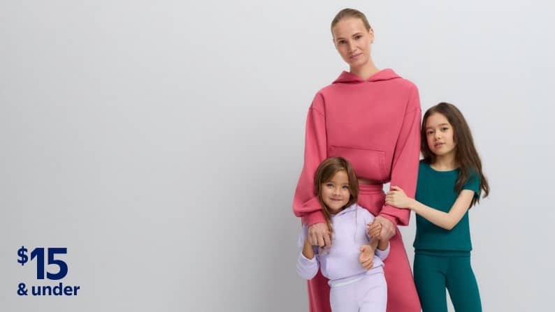 Adult in pink hoodie and pants with two children in colorful outfits, with price badge: $15 and under.