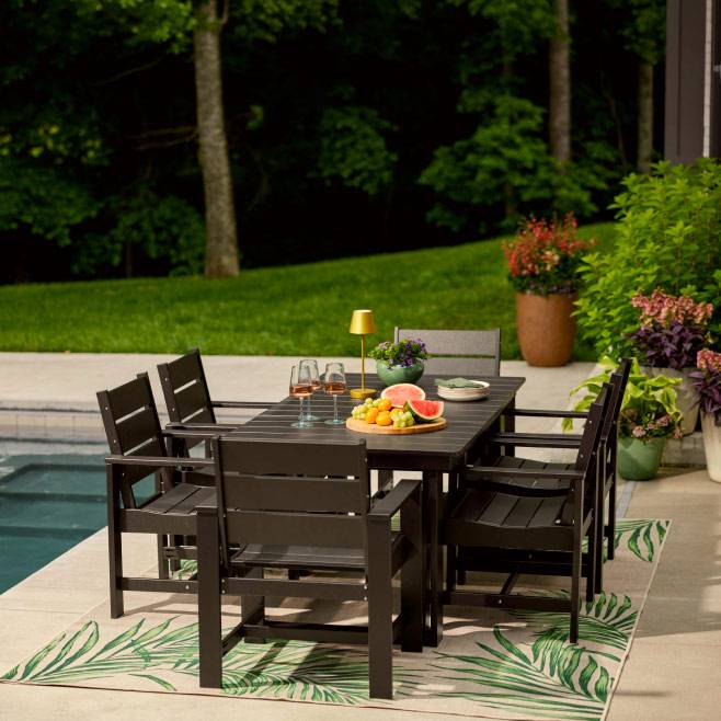 Dark brown outdoor dining table and six chairs by Better Homes and Gardens. Outdoor rug, fruit platter and wine glasses next to a pool.