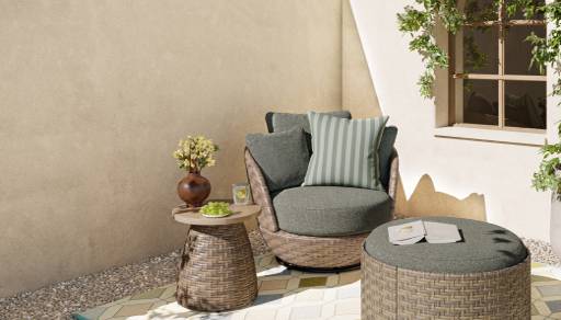 A light brown wicker patio set including a round chair and ottoman with sage green cushions and a pedestal side table.