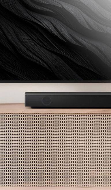 Cropped shot of rattan TV stand with soundbar & TV mounted above it. Text says: Immerse yourself. Cinematic soundbars. Shop now.