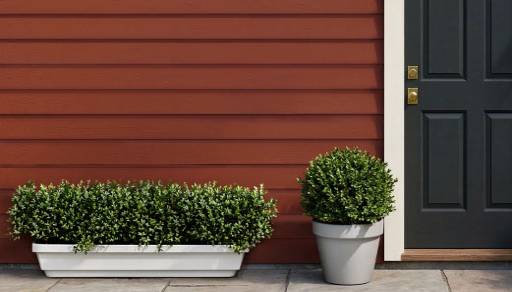 The outside of a house, with brown walls, a black door, and white trim.
