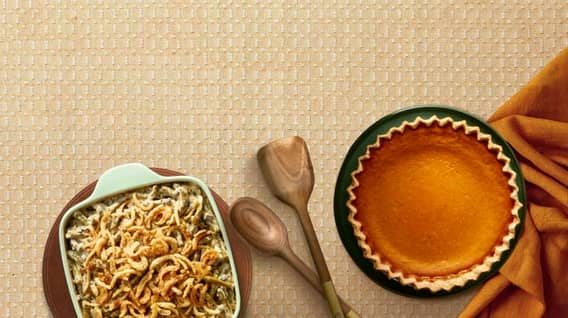 A table spread is shown with a casserole, wooden utensils and a pumpkin pie.