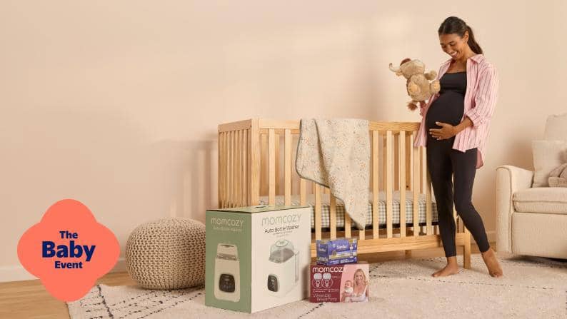 The Baby Event. Momcozy baby monitor and breast pump boxes beside a crib as a pregnant adult holds a stuffed animal.