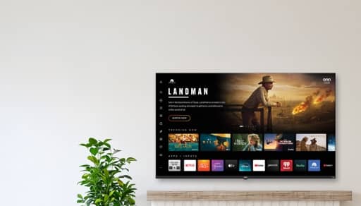 A person holding a TV against a wall, across from a TV screen showing multiple apps.
