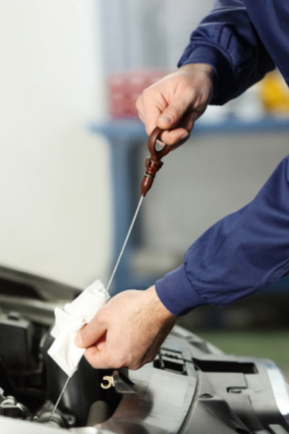 A hand working under the hood of a car.