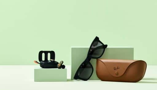 Image shows a pair of smart glasses and a case on a light green background.