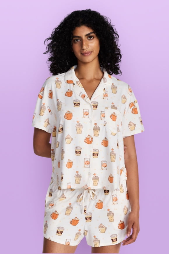 A woman wearing a white pumpkin printed pajama set is standing.