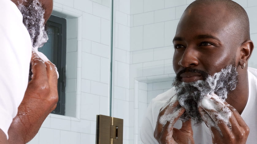 A man using Cremo beard oil in the bathroom mirror