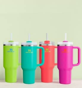 An image of multicolored Stanley tumblers on a green background.