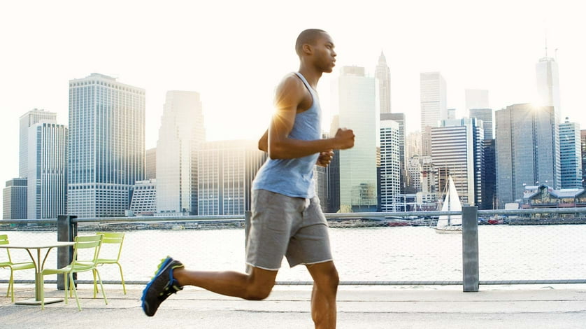 A man jogs outside with the Manhattan skyline in the background.