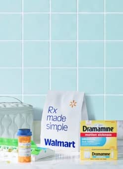 Walmart prescription bag beside a pill organizer, prescription bottle, and Dramamine motion sickness tablets.