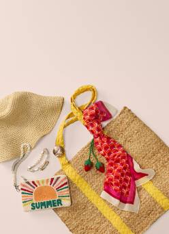 Straw hat, woven tote with yellow handles, red patterned scarf, beaded bracelets, and small summer pouch on neutral background.