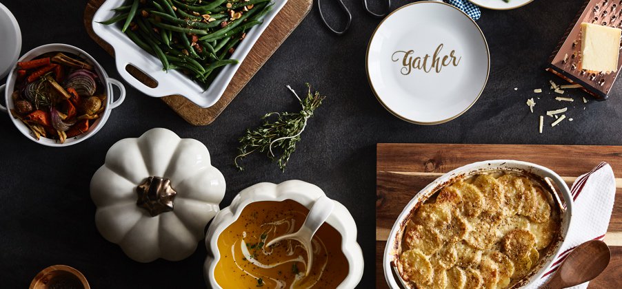 A countertop with a white ceramic pumpkin soup bowl, white ceramic casserole dish, white and gold ceramic baking dish and beautiful wood cutting boards. Links to a blog post with cooking tips for easier holiday meal prep. 