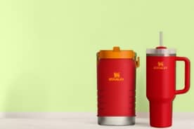 An image of multicolored Stanley tumblers on a green background.