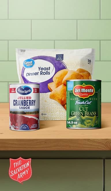 A Salvation Army logo is shown. A bag of Great Value rolls, a can of green beans and a can of cranberry sauce sits on a table