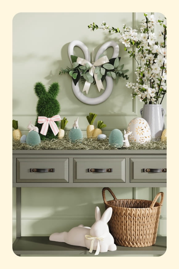 Entryway table with textured bunny and egg ornaments along with flowers and wreaths in green, blue and yellow.