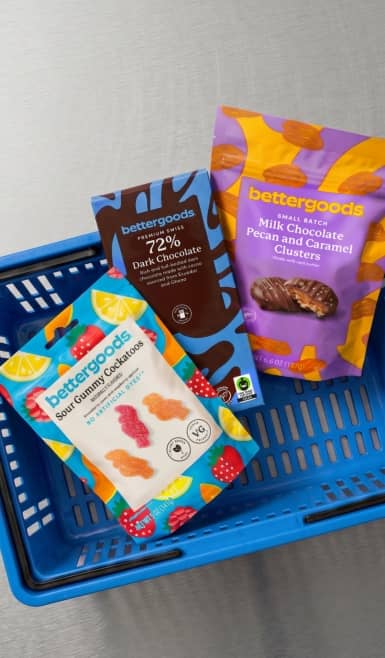 bettergoods sour gummy cockatoos, premium Swiss 72 percent dark chocolate, and milk chocolate pecan and caramel clusters in a Walmart basket.