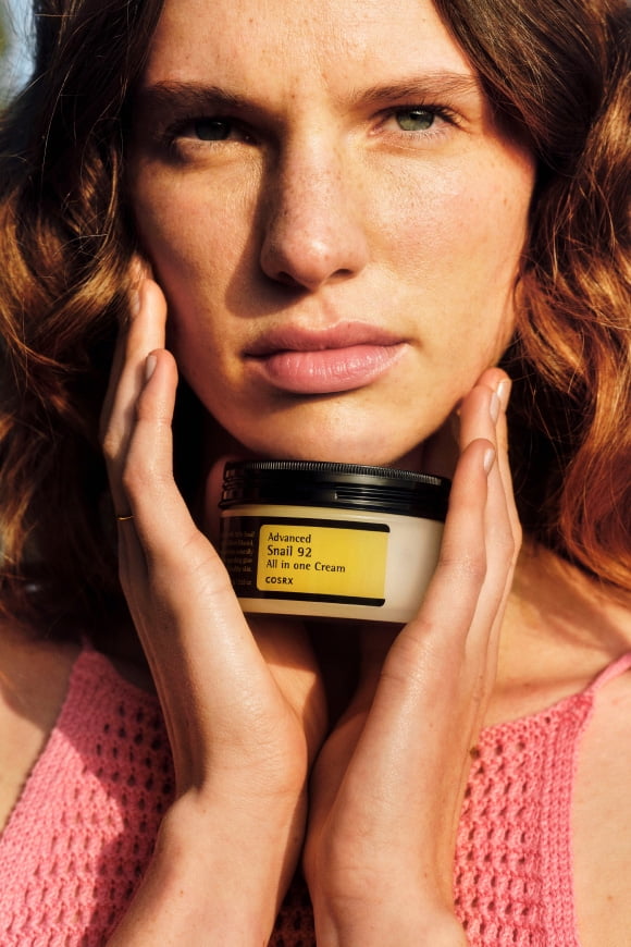 Image of a model holding a beauty product is shown.
