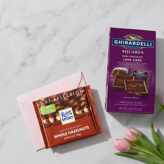 An envelope, tulips, a bag of Ghirardelli chocolates, and a Ritter Sport chocolate bar.