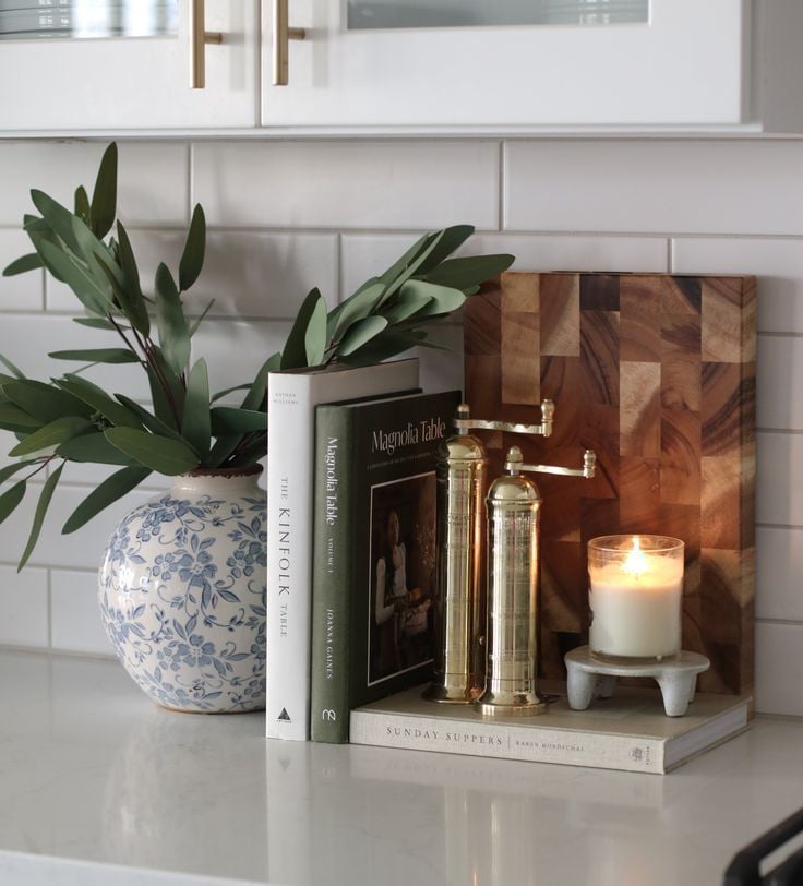 Effortless kitchen styling  means one thing -- books, brass accents, and a cozy candle for the perfect kitchen vignette. Simple, chic, and functional! Who else loves a curated countertop? , Shop post, 