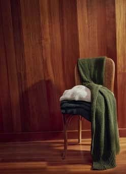 Woven throw blankets draped over a wooden chair in a warm, cozy interior.