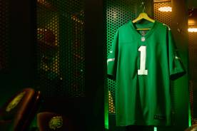 A green NFL jersey is shown with the number one on the front hanging inside a locker room.
