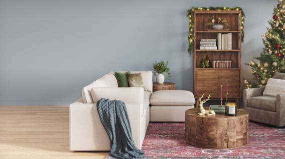 A dusty blue living room features an accent chair, coffee table, Christmas tree and festive decor.