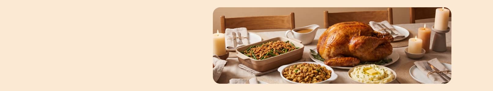 Roast turkey with stuffing, green bean casserole, mashed potatoes and rolls on a candlelit dining table.
