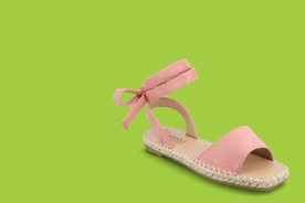 Image shows pink Journee Emelie Espadrille flat sandals with a bow detail on a green background.