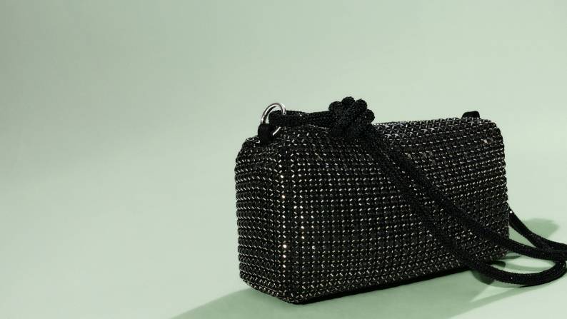 Small black rectangular rhinestone handbag with braided strap and knotted detail.