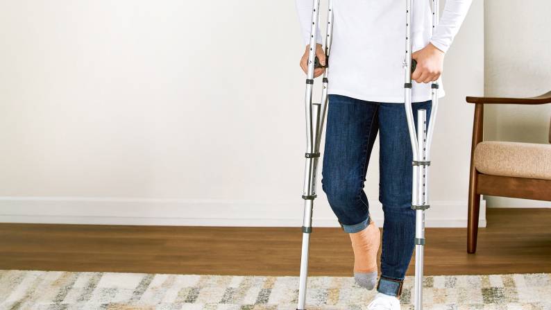 Man using crutches for support walking around house.