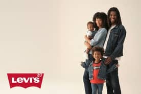 A smiling family wears denim outfits. The mom holds a baby, the father wears a jean jacket and a child in front wears a red Levi’s shirt and jacket.