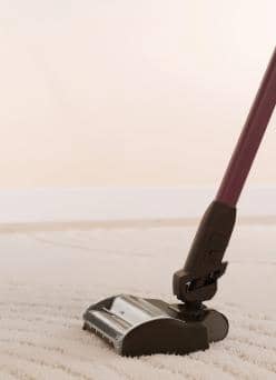 Vacuum cleaner head with a red handle cleaning a light carpet.