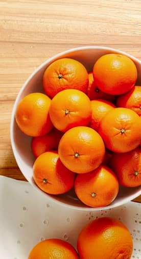 A bowl of mandarins are shown on a kitchen counter.