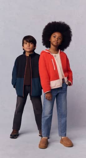 A girl wears a zip fleece jacket, jeans and clogs with faux shearling lining. A boy wears a fleece jacket, crewneck sweater, jeans and hiker boots.