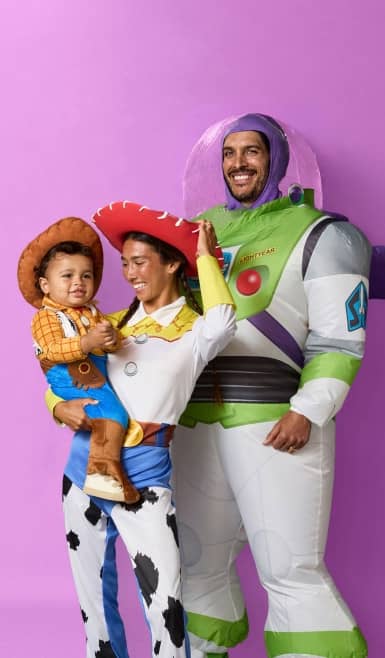 Dad, in a Buzz Lightyear costume, stands next to Mom in a Jesse costume, who smiles at her baby dressed as Woody.
