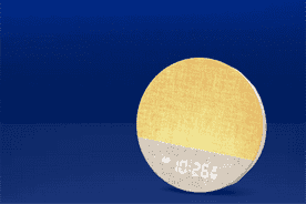 Image shows a yellow and gray Dreamegg alarm clock with a digital display on a blue background.