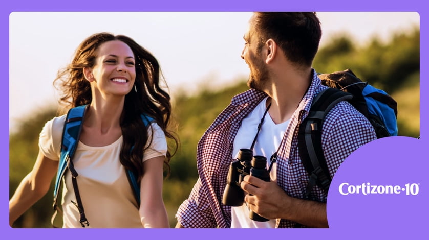 Two people wearing backpacks smile while outside.