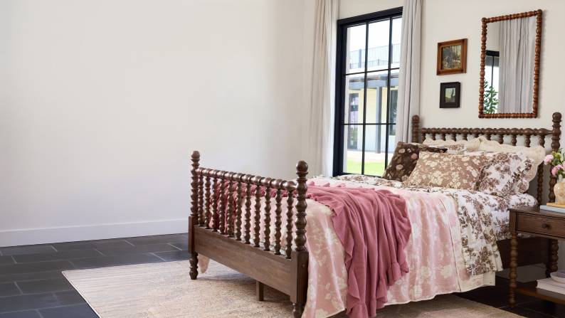 A bedroom with floral patterns & pillows on the bed.