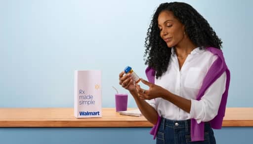 A woman holds a prescription bottle next to a smoothie and a Rx Made Simple Walmart bag.