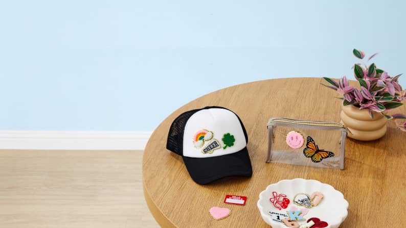 Blue banner image with crafting table, iron patches, hat and text: Personalize your work. Design with Hello Hobby. Shop now.