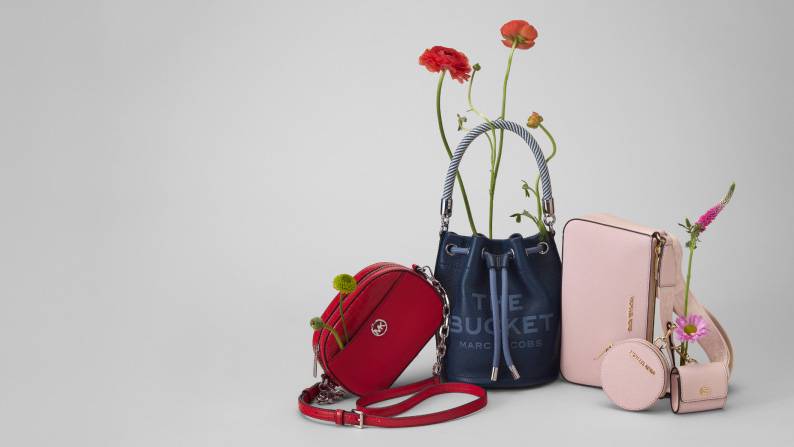 Red crossbody bag, navy bucket bag, and pink quilted shoulder bag with flowers; trendy designer-inspired summer accessories.