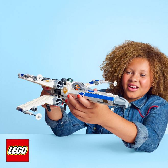 Lego. A child smiles while holding a detailed Lego spaceship toy.