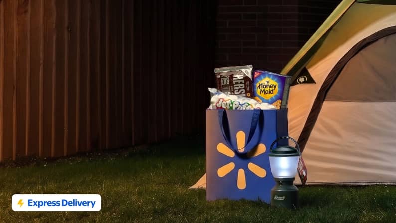 Express Delivery. A tent outdoors next to a lantern and a Walmart bag filled with chocolate bars, graham crackers and marshmallows.
