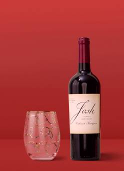 A wine glass and a bottle of Josh wine.