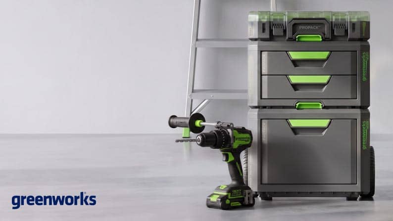 Greenworks logo. Toolbox with stack system and power tools on the ground with a ladder in the background.